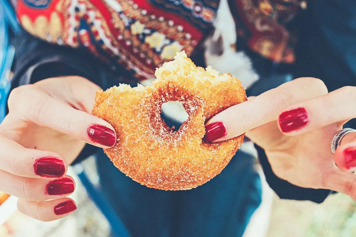 Two hands breaking open a cinnamon-sugar doughnut